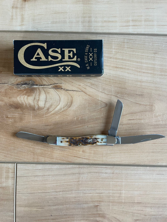 A stainless steel hunting knife with a bone handle and nickel silver bolster, displayed in front of its box labeled 'CASE'.